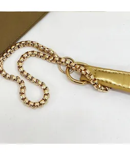 Close-up of golden box chain strap and olive green leather detail on crossbody bag