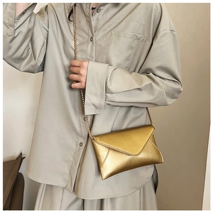 Macro view of metallic gold envelope crossbody bag with glossy crinkled texture