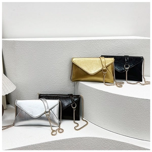Three envelope clutch bags in silver, gold and black with chain straps on geometric stands