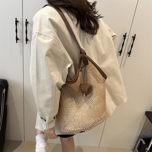 Large woven tote bag with brown leather straps shown on shoulder for summer casual style