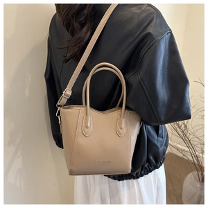 Detail of beige leather bucket bag with FASHION embossed logo and adjustable strap