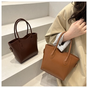 Close-up of dual-tone tote bags in dark brown and caramel leather with FASHION embossing