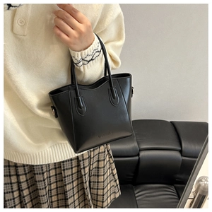 Detailed view of black PU tote bag texture with FASHION lettering and metal rings