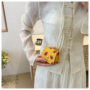 Detail of yellow cherry print mini wallet with gold chain strap and snap closure