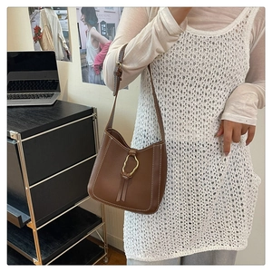 Detalle de bolso cubo marrón con pespuntes blancos y hebilla de metal dorado