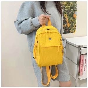 Detail of a bright yellow nylon backpack with side pockets and smooth double zippers