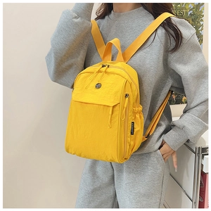 Detail of a bright yellow waterproof nylon backpack featuring dual zippers and brand label