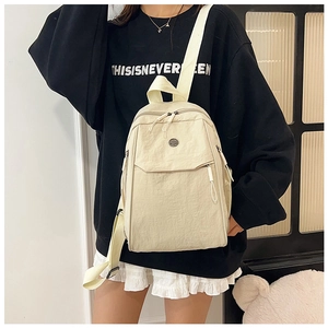 Detail of cream nylon backpack featuring lightweight material and adjustable straps
