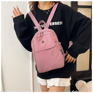 Detail view of pink nylon backpack with multiple zipper pockets and branded fabric label