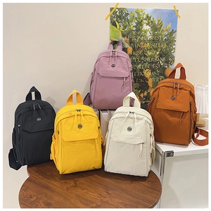 Detail of multi-color nylon backpacks in black, yellow, purple, cream, and orange