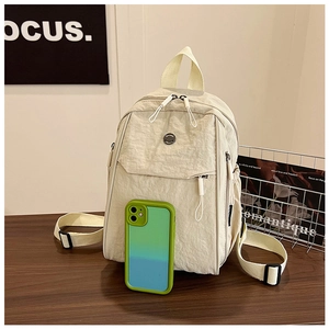 Detail of off-white nylon backpack with adjustable straps and side pocket on wooden table