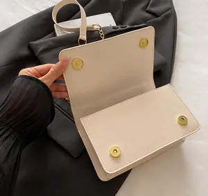 Detail view of cream flap bag showing gold hardware and spacious interior compartment