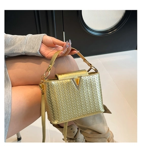 Détail du sac à main tissé doré avec fermoir en V et poignée en cuir élégante