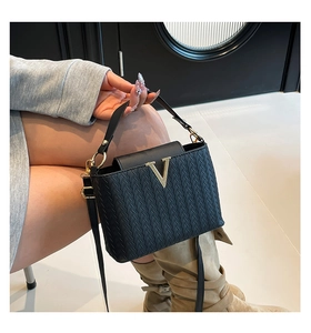 Détail du sac bandoulière tressé noir avec boucle en métal V doré et bandoulière