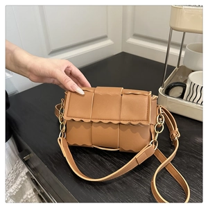 Détail du sac bandoulière marron tressé montrant des bords ondulés et une texture mate