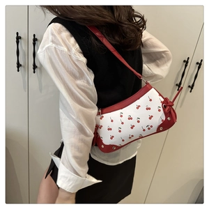 Detail of red and white cherry print shoulder bag with metallic studs and knot accents