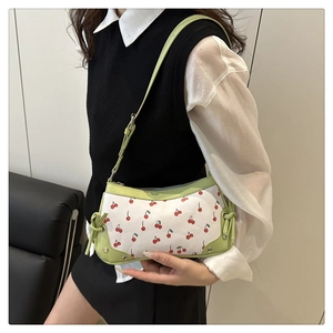 Close-up of white underarm bag featuring red cherry prints and light green trim details