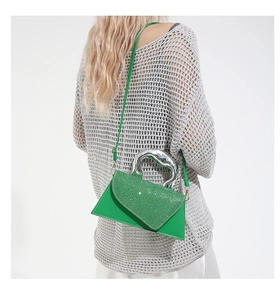Detail of green crossbody bag with rhinestone flap and silver metallic handle on model