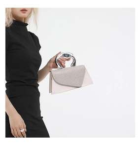 Detail of glittery flap and unique metallic silver handle on creamy white mini handbag