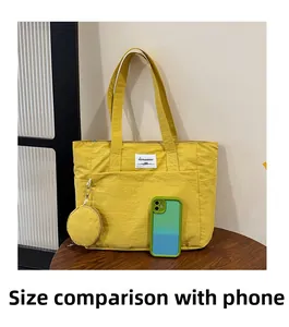 Yellow nylon tote bag size comparison with mobile phone showing spacious interior