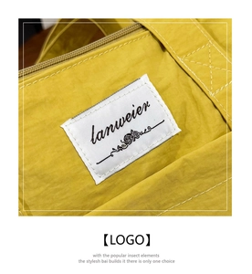Detail of a bright yellow nylon travel bag showing stitching and logo woven label