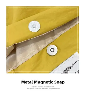 Detailed close-up of hardware magnetic buckle on yellow fabric tote bag with embroidery