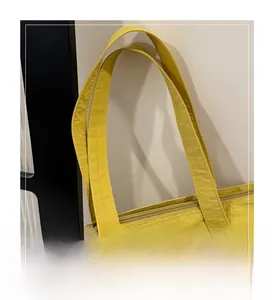 Detail of yellow canvas tote bag handles and smooth zipper closure construction