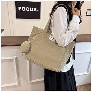 Detailed view of khaki canvas tote bag with side coin purse shown on female shoulder