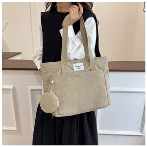 Close-up of beige nylon tote bag with texture detail and a round mini coin purse attachment