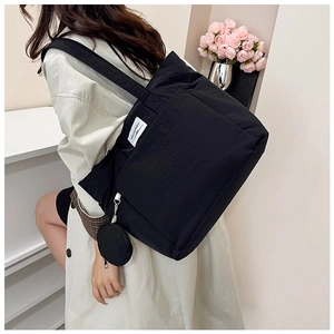 Detail of black canvas tote bag showing the side zipper coin purse and white fabric label