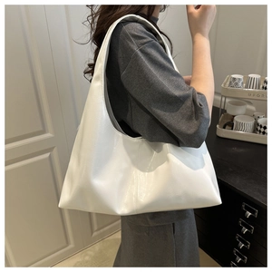 Detailed view of a white large capacity faux leather hobo bag worn by a model for daily commute