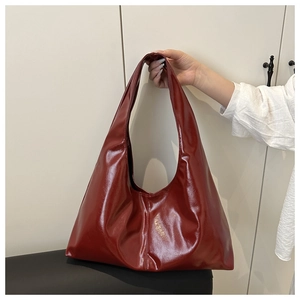 Detail of burgundy glossy patent leather tote bag with wide shoulder strap