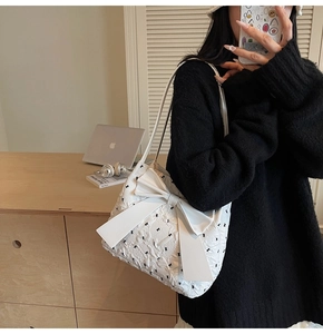 Détail du sac à bandoulière blanc avec petits nœuds noirs et grand nœud décoratif 3D