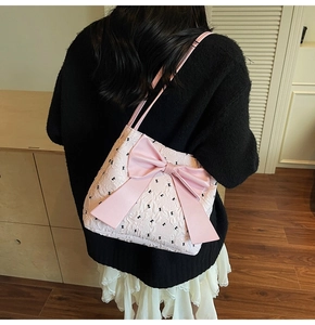 Vue portée du cabas matelassé rose avec motifs de nœuds noirs et grand nœud en cuir