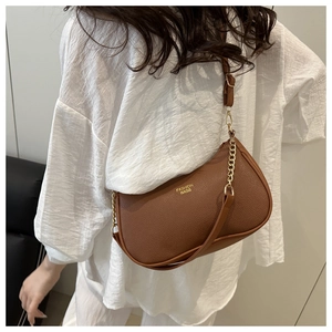 Close-up of brown litchi pattern leather texture and golden metal chain detail on the bag
