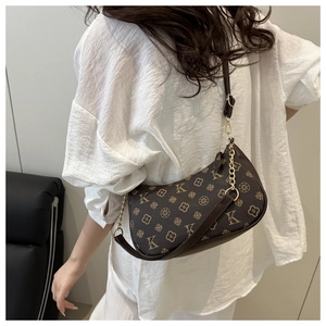 Close-up of brown textured underarm bag with vintage monogram and gold chain