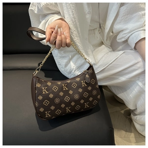 Detail of dark brown monogram pattern with golden chain handle and leather strap on a handbag