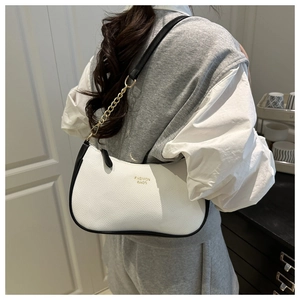 Close-up of white pebble leather bag with black trim, gold chain, and fashion lettering