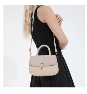 Detalle del bolso bandolera beige texturizado con hebilla de herradura dorada en modelo