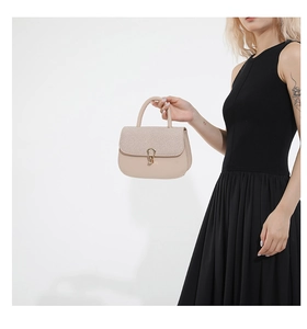 Detalle de bolso silla beige con solapa trenzada y hebilla de herradura dorada