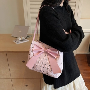 Sac à bandoulière rose avec grand nœud et motifs papillons porté par un mannequin