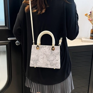 Chic grey crossbody bag with floral pattern and woven round handle in daily use