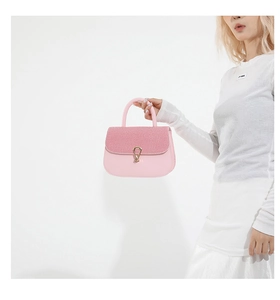 Detalle del bolso de silla rosa con solapa trenzada y cierre de hebilla dorada