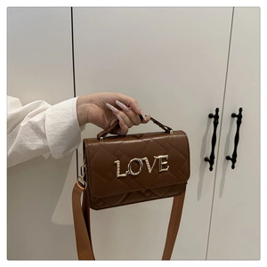 Detailed view of brown quilted crossbody bag with gold LOVE emblem and shoulder strap