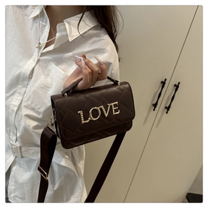 Detail of dark brown quilted crossbody bag with gold LOVE metal lettering and smooth handle