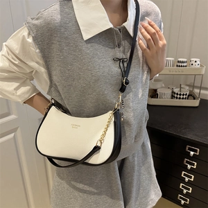 Chic black and white contrast hobo bag with gold chain strap shown on a model