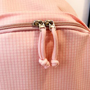 Detail of pink plaid fabric travel bag showing durable double zipper closure design