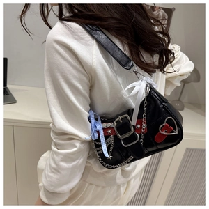 Detail of Y2K black shoulder bag with heart buckle, metal chains and bow accents