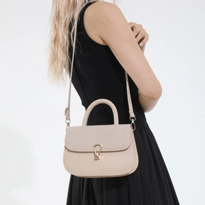 Minimalist beige saddle bag with woven texture and gold buckle shown on a model