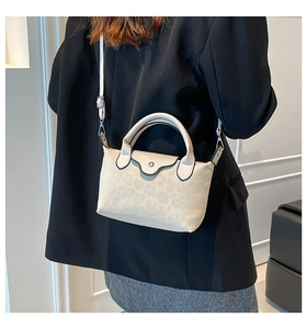 Vista detallada de un bolso beige con estampado de leopardo llevado por modelo